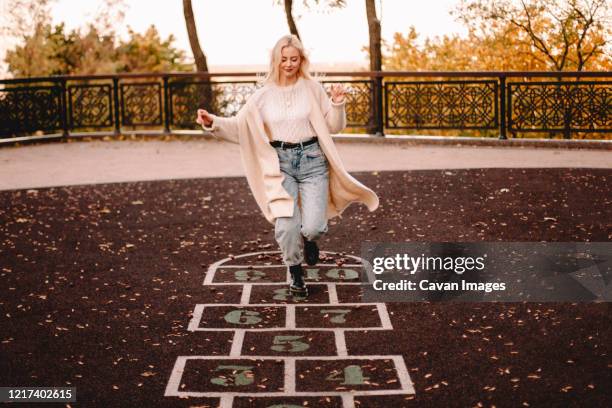young woman playing hopscotch in park during autumn - hopscotch stock pictures, royalty-free photos & images
