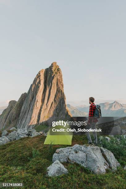 mann steht in der nähe des zeltes in der nähe des segla-gebirges auf senja - insel senja stock-fotos und bilder