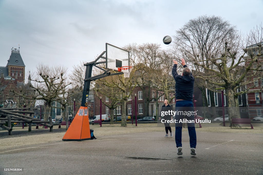 Young woman and mature man playing basketball in the park