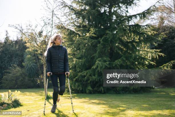 junge frau auf krücken entspannt sich im garten - crutch stock-fotos und bilder