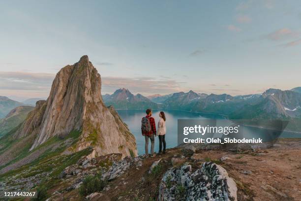 vrouw en man die zich met mening op eiland senja bevinden - midnight sun norway stockfoto's en -beelden