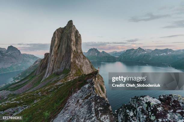 frau sitzt und schaut segla in der nähe des berges auf der insel senja - insel senja stock-fotos und bilder