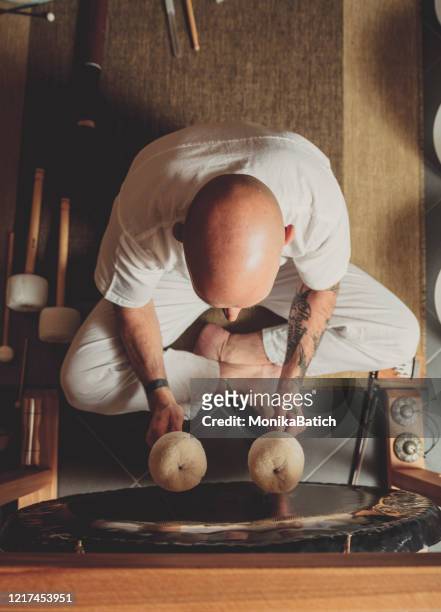 hombre adulto jugando al gong - gong fotografías e imágenes de stock