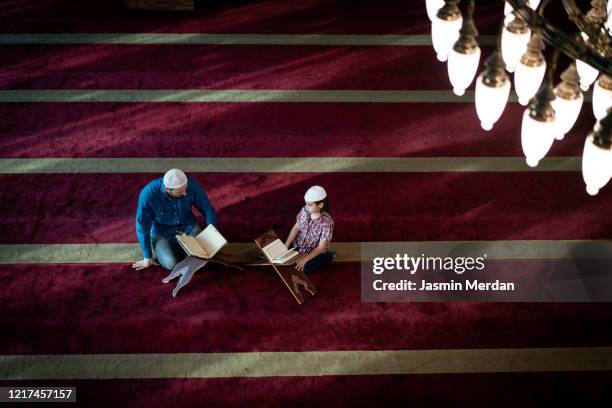 muslim teacher and little boy reading koran inside beautiful mosque - imam stock pictures, royalty-free photos & images