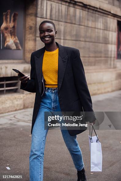 Akon Model Model Akon Changkou wears a black blazer, orange knit top, and blue ...