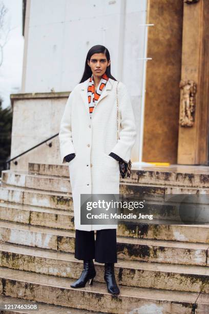 Model Pooja Mor wears a white coat, Balenciaga scarf, black boots after the Akris show during Paris Fashion Week Fall/Winter 2020 on March 02, 2020...