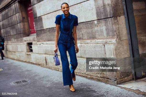 Model Janaye Furman wears a fitted denim jumpsuit, a small purple bag, and brown leather boots after the Giambattista Valli show during Paris Fashion...