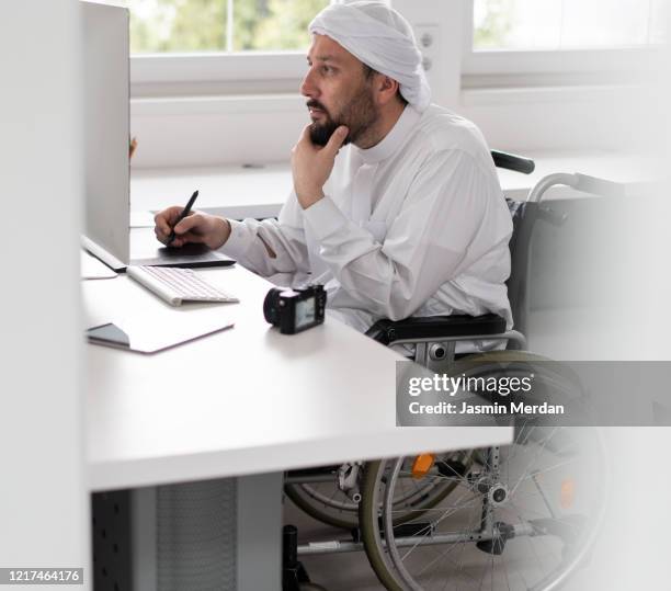 arabic man in wheelchair at office desk with computer - ramadan dubai stock pictures, royalty-free photos & images