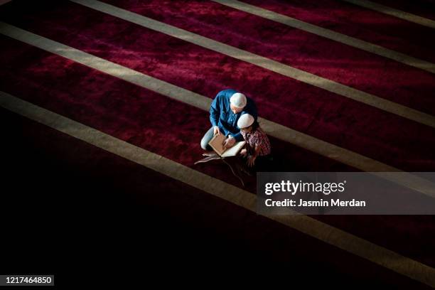 muslim teacher and little boy reading koran inside beautiful mosque - imam stock pictures, royalty-free photos & images