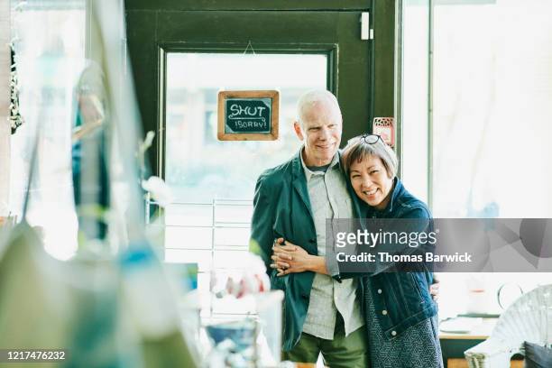 Portrait of smiling shop owner couple embracing in store