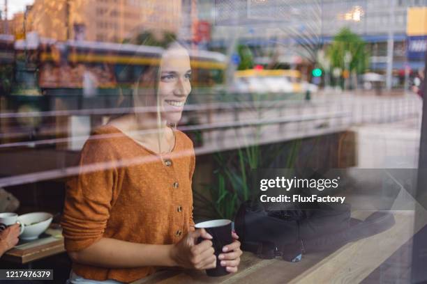 mooie vrouw die van koffie bij een koffie geniet terwijl het kijken door een venster - finland stockfoto's en -beelden