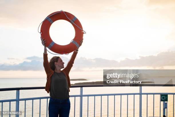 cheerful woman holding a life buoy on a cruise ship deck - spring finland stock pictures, royalty-free photos & images