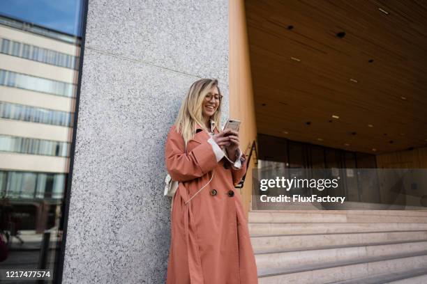 beautiful fashionable woman text messaging on the street - finland spring stock pictures, royalty-free photos & images