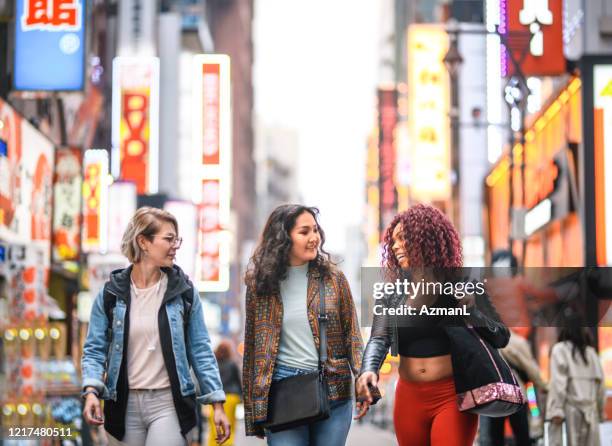 female tourists walking together through shinjuku at dusk - the unity tour stock pictures, royalty-free photos & images
