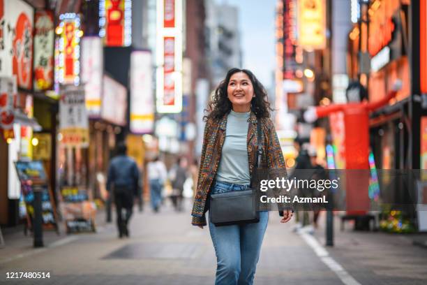 glimlachende mongoolse vrouw die district shinjuku bij schemering onderzoekt - mongoolse etniciteit stockfoto's en -beelden