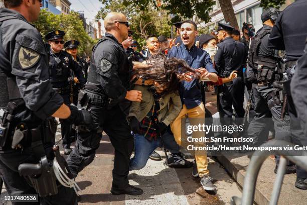 Police officer pushes a person to the ground when a group of anti-police protesters blocked Market Street in an attempt to shut down the annual Pride...