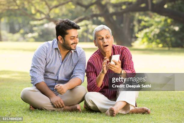 father and adult son relaxing in park stock photo - father stock pictures, royalty-free photos & images