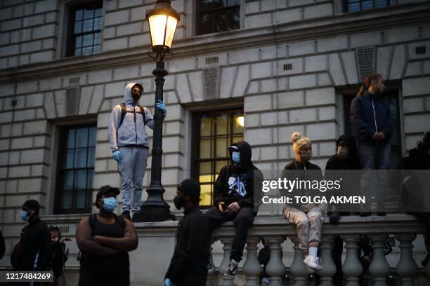 Protestors wearing PPE , including a face mask as a precautionary measure against COVID-19, stand and sit on a wall in Parliament Square, during an...