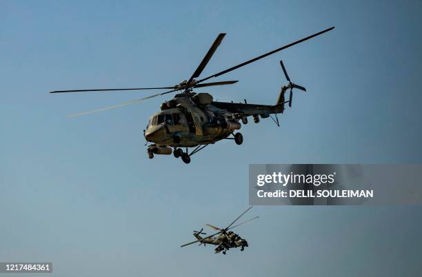 Russian Mil Mi-17 and Mil Mi-24 military helicopters fly over the northeastern Syrian town of al-Malikiyah at the border with Turkey, on June 3, 2020.