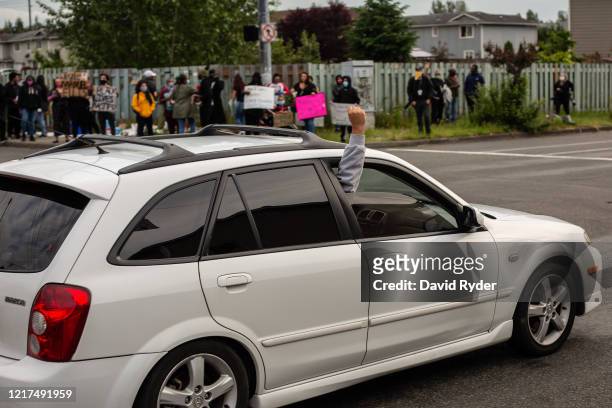 Person raises their fist from a passing car as others gather for a vigil in memory of Manuel Ellis, a black man whose March death while in Tacoma...