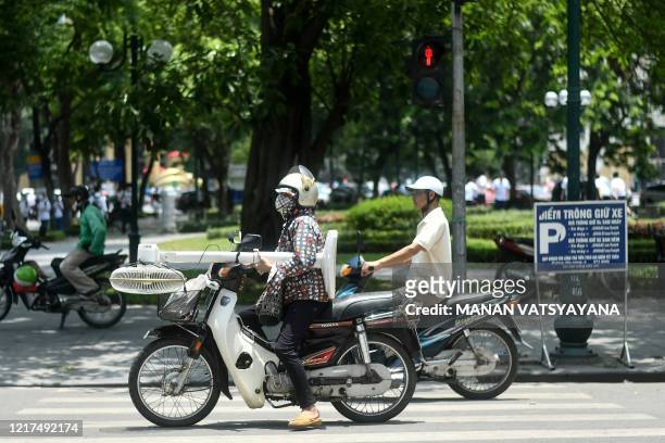Motorist carries a fan on a motorcycle as the temperature soars in Hanoi on June 4, 2020.