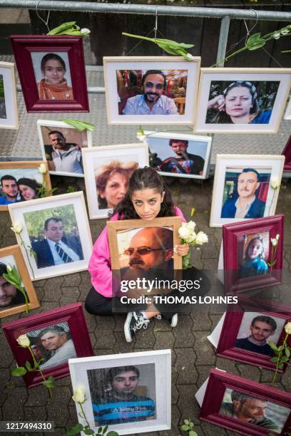 Syrian campaigner Wafa Mustafa sits between pictures of victims of the Syrian regime as she holds a picture of her father, during a protest outside...