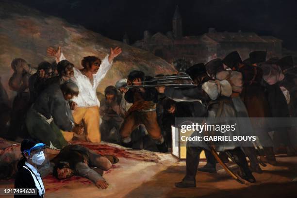 Museum worker wearing a face mask and shield stands next to the painting "The Third of May 1808" by Spanish painter Francisco Goya at the Prado...