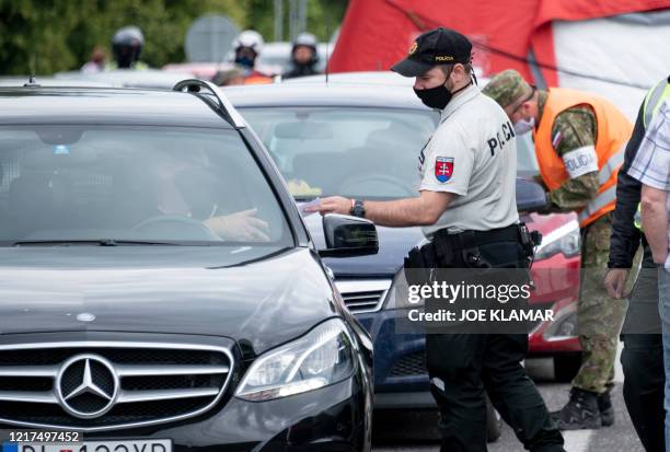 Slovak police officer checks the papers of travelers crossing the Bratislava-Berg border crossing between Austria and Slovakia during the coronavirus...