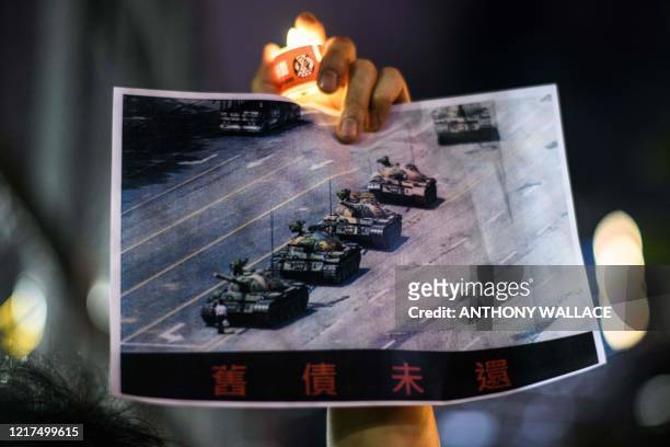 Man holds a poster of the famous 'Tank Man' standing in front of Chinese military tanks at Tiananmen Square in Beijing on June 5 during a candlelit...
