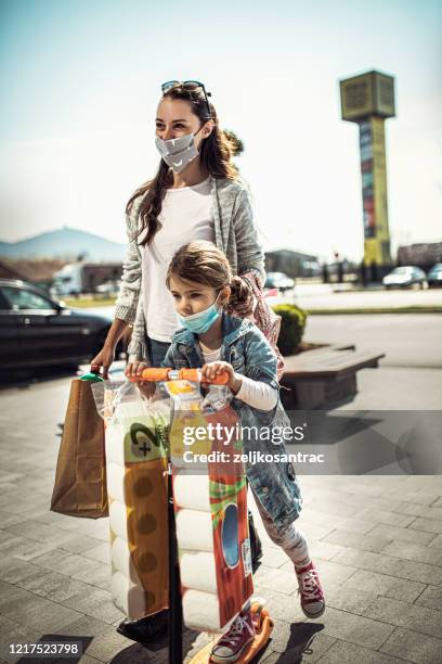 woman with her daughter wearing a protective mask shopping covid -19 - buying toilet paper stock pictures, royalty-free photos & images