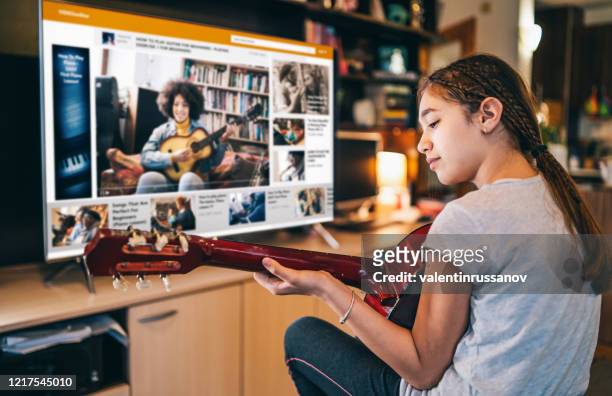 ragazza che suona una chitarra con video online teleconferenza a casa in isolamento - television show foto e immagini stock