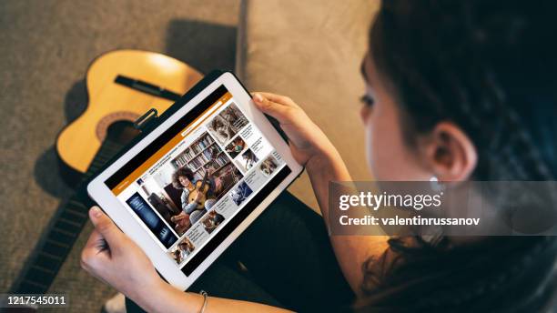 fille regardant une leçon en ligne de vidéo de guitare à la maison dans l’isolement - television show photos et images de collection