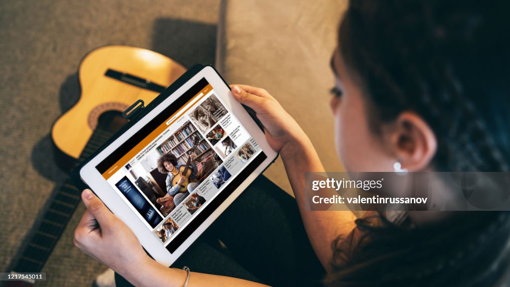 Girl watching a guitar video online lesson at home in isolation