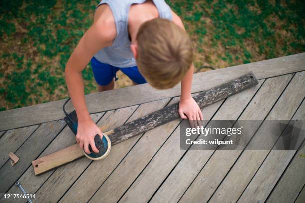 boy using orbit sander to clean wooden plank top view - backyard deck stock pictures, royalty-free photos & images