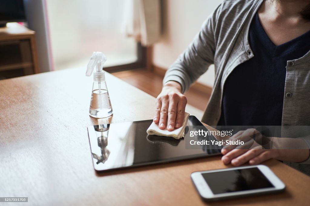 Woman disinfects digital tablet with alcohol