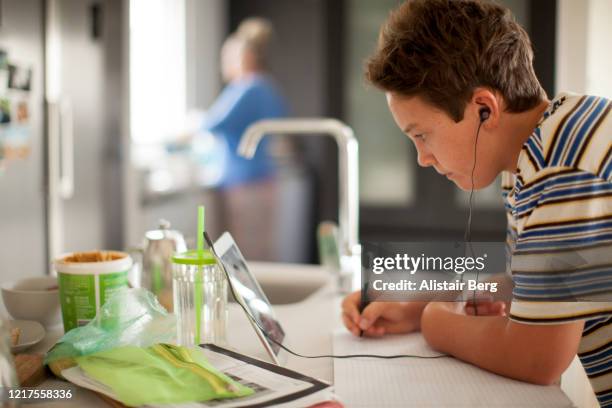 young student working on digital tablet in his kitchen during lockdown - abstand halten infektionsvermeidung stock-fotos und bilder