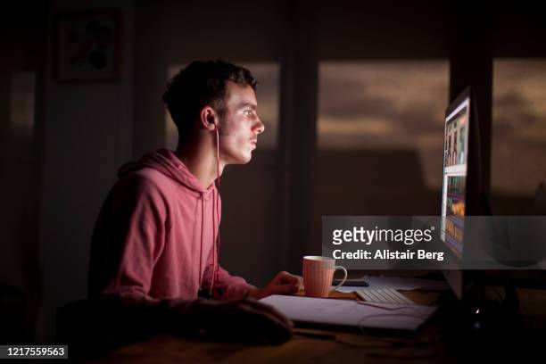 student working on his computer in the evening during lockdown - computer virus - fotografias e filmes do acervo