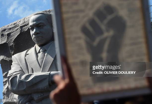 Statue of Martin Luther King Jr. Is seen as demonstrators raise a fist image at The Martin Luther King Jr. Memorial to protest the death of George...