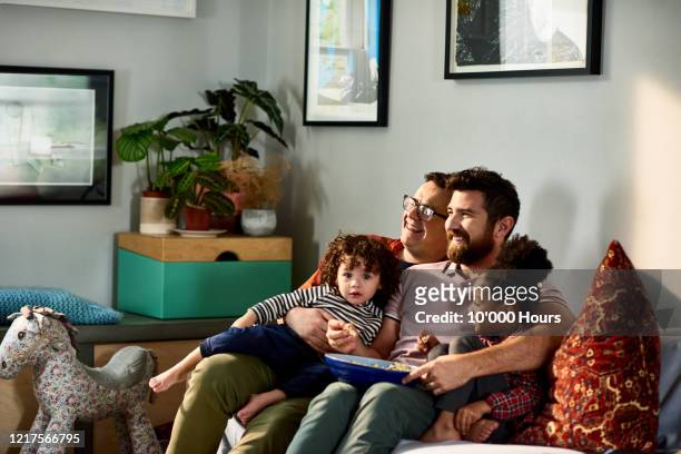 cheerful family with young children on sofa - familia viendo television fotografías e imágenes de stock