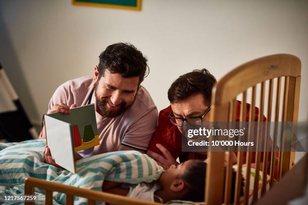 adoptive fathers reading bedtime story to daughter - bedtime fotografías e imágenes de stock