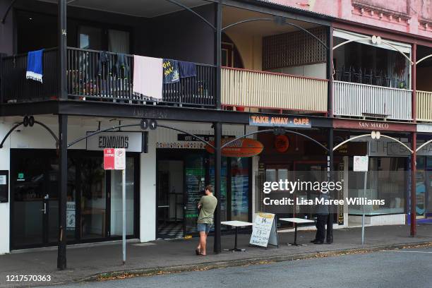 Shoppers queue outside a takeaway store on Pacific Street on April 08, 2020 in Newcastle, Australia. Public gatherings are now limited to two people,...