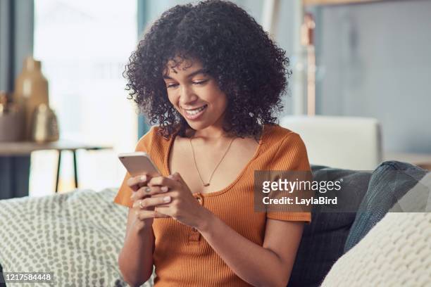 ihre social-media-fans auf dem laufenden halten - african lady sitting and looking at her smartphone stock-fotos und bilder