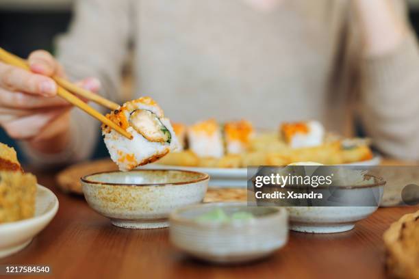 woman eating sushi rolls - plate eating table imagens e fotografias de stock