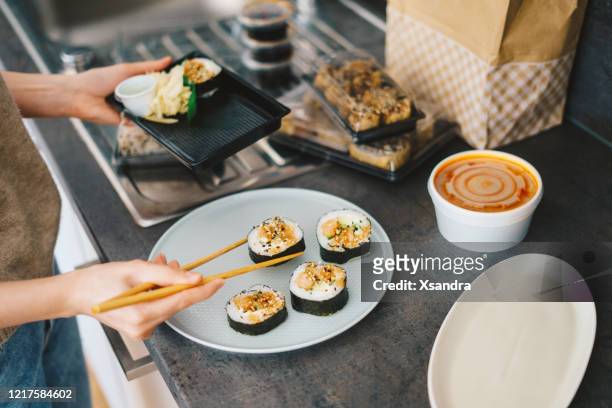 woman unpacking takeaway sushi at home - sushi stock pictures, royalty-free photos & images