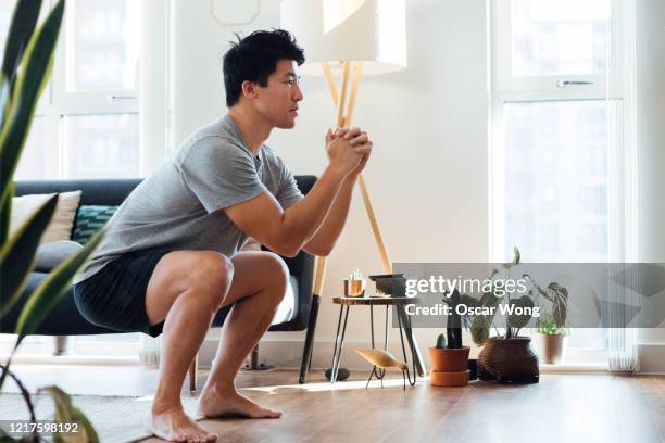 young man doing squats at home - bodyweight training stock pictures, royalty-free photos & images