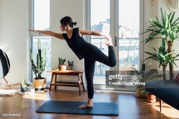 young woman doing yoga exercise at home - asian exercise stock-fotos und bilder