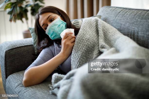 sick woman with face protective mask lying in bed - caucasian woman sick in bed coughing stock pictures, royalty-free photos & images