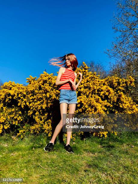 girl throwing hair to side by yellow gorse bush - 13 year old girls in shorts stock pictures, royalty-free photos & images