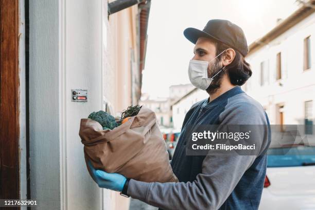 a man is delivering a bag of vegetables and fruit - essential services stock pictures, royalty-free photos & images