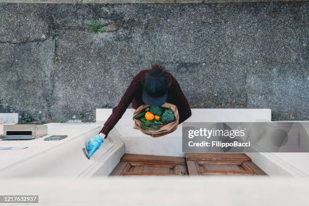 vista aérea de uma jovem entregando um saco de legumes e frutas - ringing doorbell - fotografias e filmes do acervo